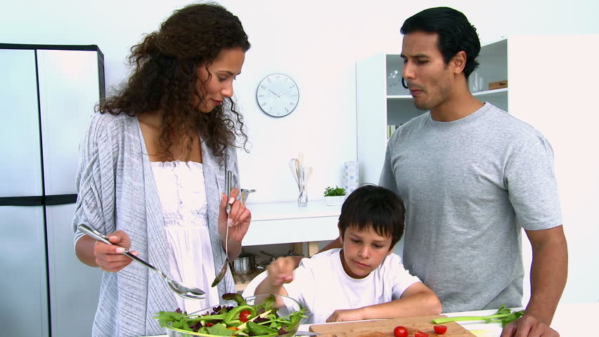 Woman cooking a salad with her son in the kitchen