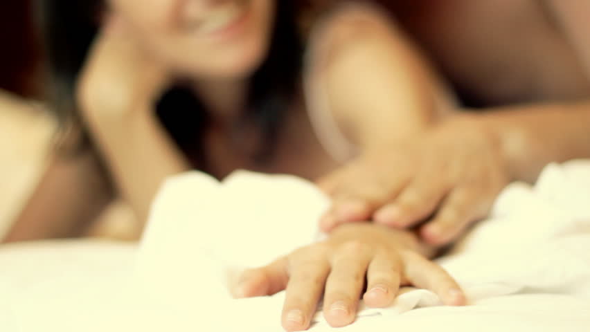 Lovers holding hands in bed 