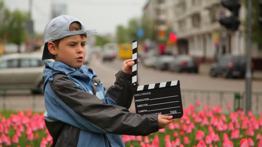 boy claps clapperboard and goes out of frame 