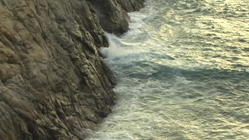 Fisherman with rocks and savage ocean waves