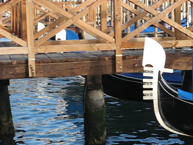 Venice: Detail of a moving gondola prow near a wooden mole