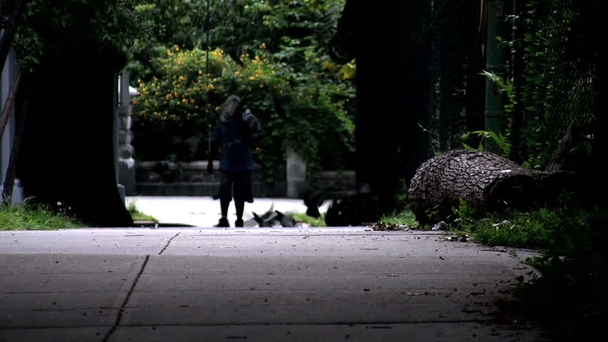 Silhouette of a man walking down a sidewalk.  Birds fly up around him.