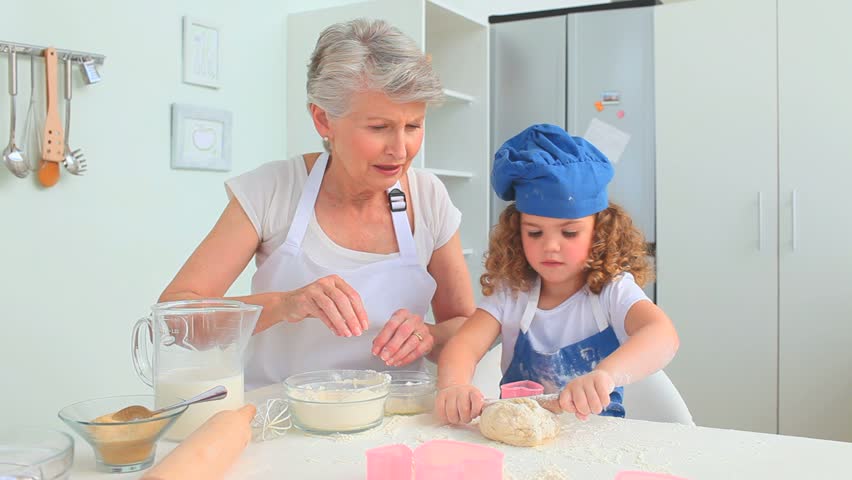 Adorable child learning to cook with her grandmother
