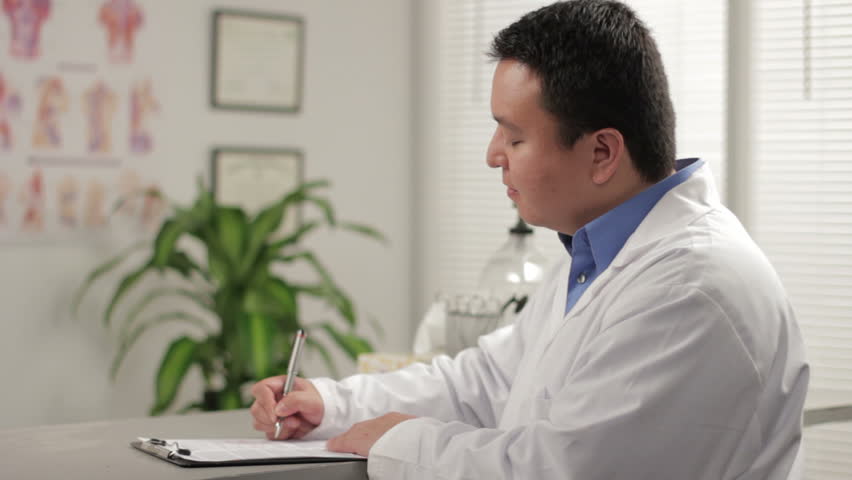 Doctor writing, then looking at camera