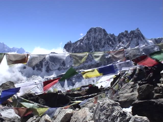 Buddhist prayer flags on Gokyo Ri in Nepal, with Mount Everest towering above in the distance.