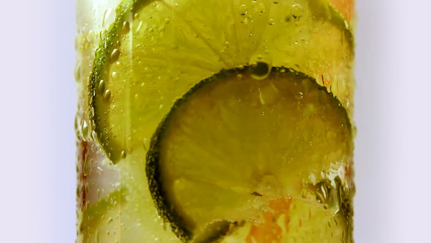 Rotating glass of lemonade with lime green. Isolated. 3 takes.
