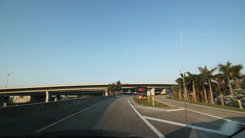 Florida highway. Under an interchange. Driving on a highway in southern Florida . View through front windshield including side mirror. Going under several overpasses. 