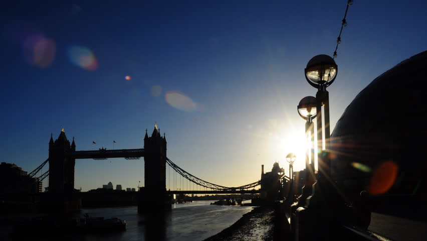Early morning sunrise time-lapse behind the famous Tower Bridge over the River Thames in London, England. The sun moves behind lights on the embankment and then behind City Hall.