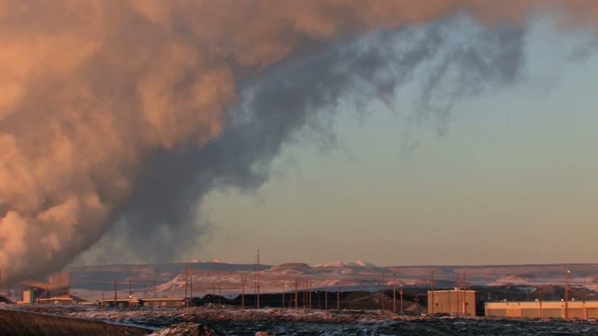 Video pan left of pollution, smoke and steam discharged from a coal powered electrical generation facility in New Mexico. Pollution contamination, pollution and global warming and climate change. 
