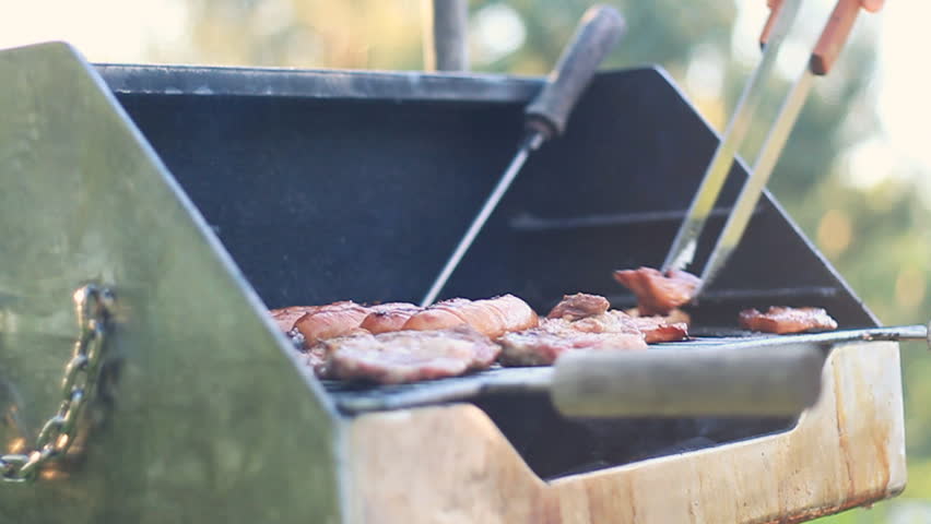 Man cooking meat on the barbecue grill, outdoors, camera stabilizer shot