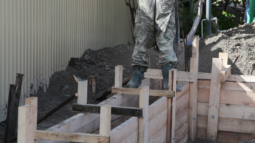 Worker pours the foundation of building