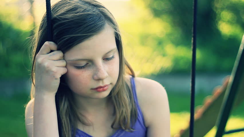 Sad preteen girl sitting on swing  