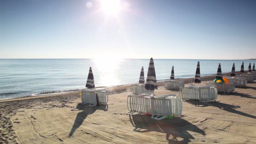 Many parasols and deckchairs standing on beach at sunny day, panoramic view 
