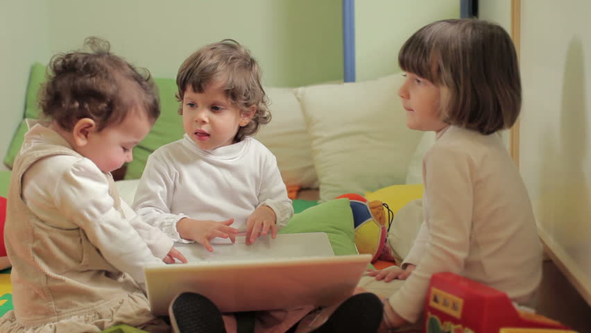 Babies playing with laptop computer in kindergarten