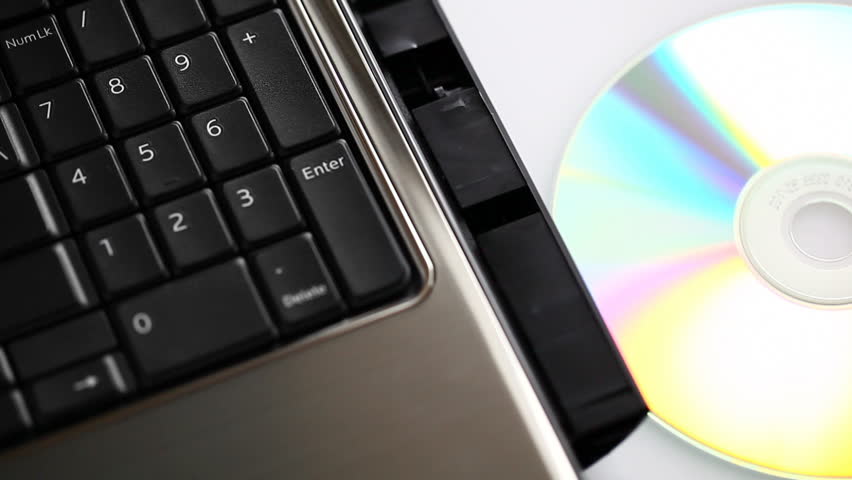 Male hand inserting/ejecting a disc from a laptop.