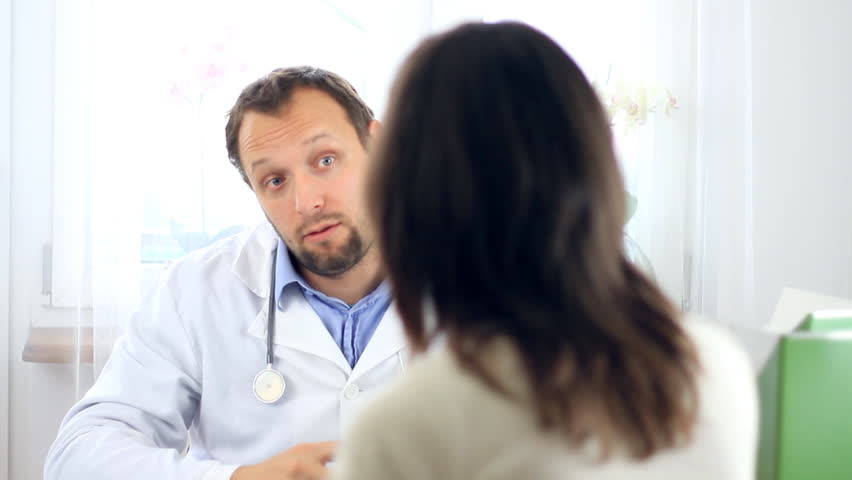 Male doctor giving green apple to female patient