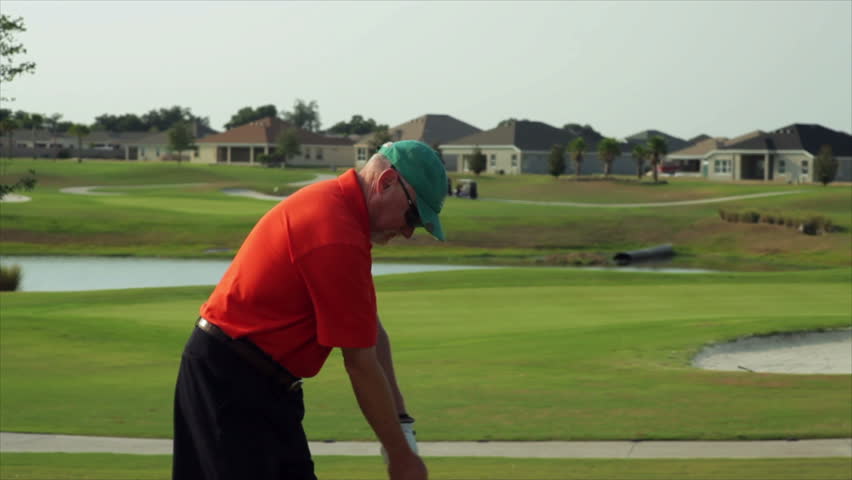 A golfer grabs his lower back and winces in pain during a golf swing.