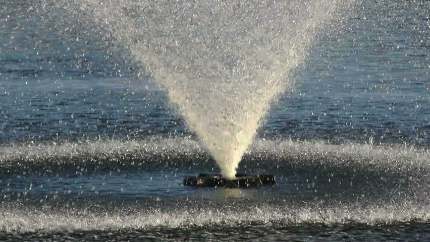 Slow motion, Ornamental fountain spews water, its falling droplets form dancing circles in blue pond. 1080p