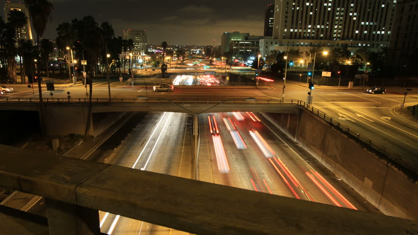 Sliding time-lapse shot above bridge railing revealing freeway traffic 