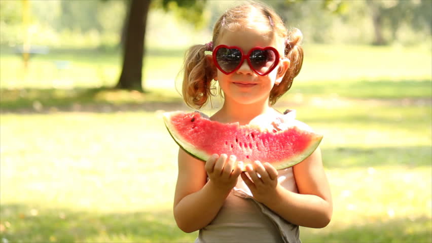 little girl with sunglasses eats watermelon