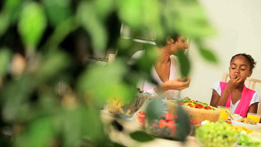 Young african american family sitting at the table sharing a healthy lunch together at home 
