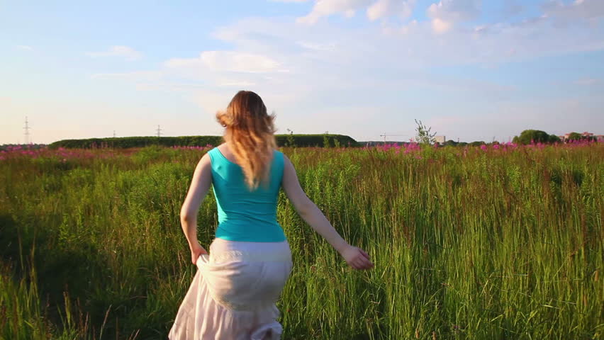 Young woman running in field.