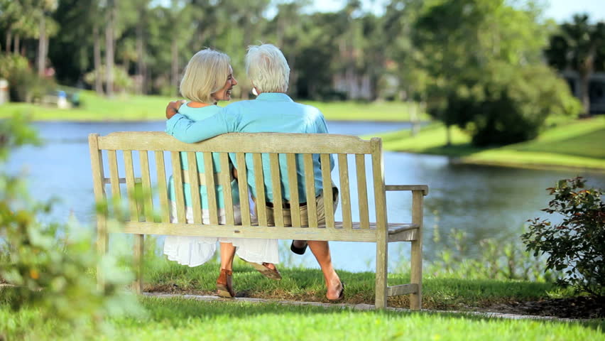 Attractive healthy senior couple enjoying each others company relaxing in a park