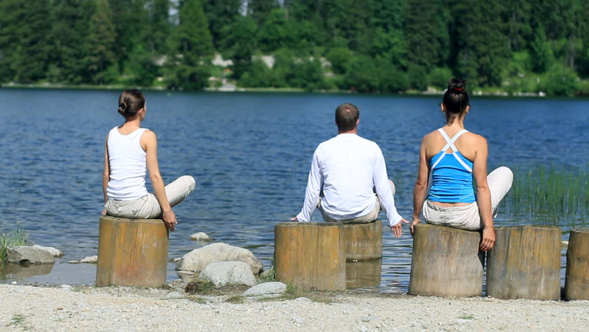 Group of meditating people by the lake