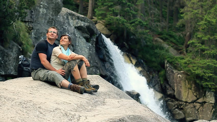 Happy couple relaxing by the beautiful waterfall, slow motion 
