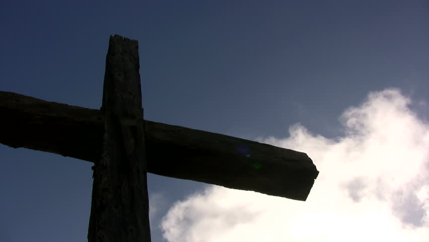 A large cross with white clouds floating behind it.