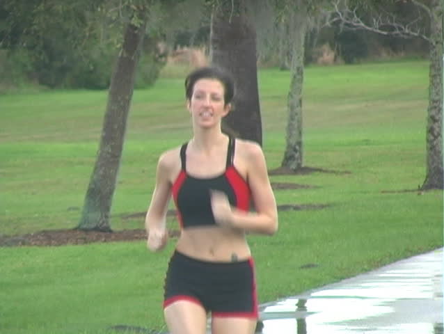 A beautiful young woman jogging outdoors toward the camera.