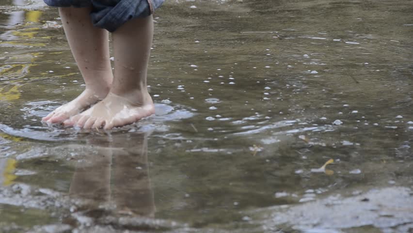feet of a kid enjoying to walk barefooted through puddles