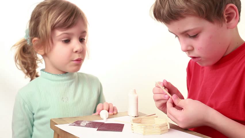 Girl tell something to boy which apply glue on match and attach it to wall of match house, she just touch the cap of glue bottle but it made boy angry