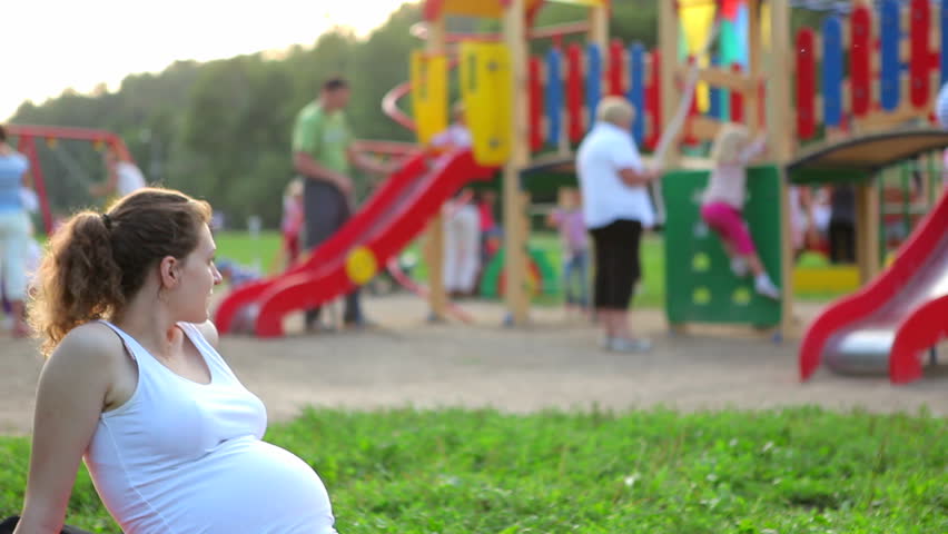 Pregnant woman watching the children on the playground