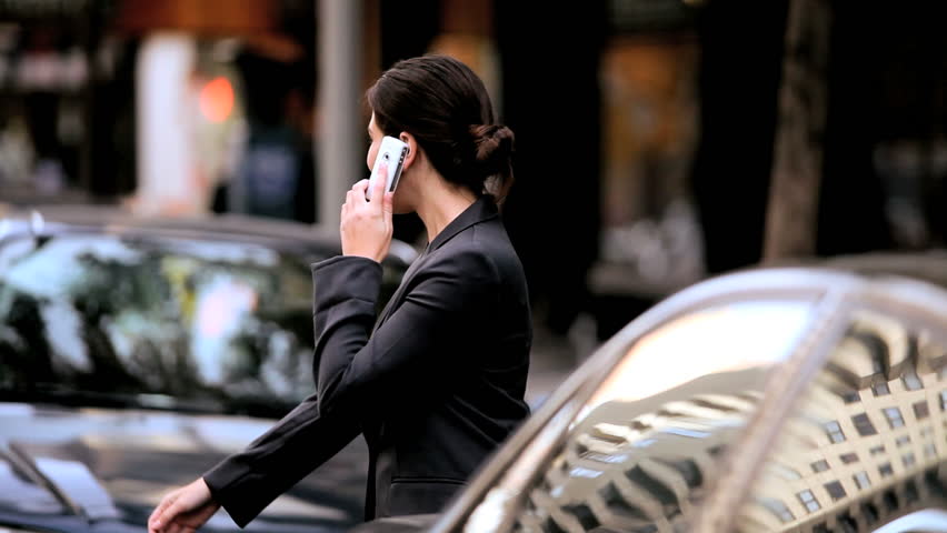 Smart young businesswoman with a cell phone on the streets of New York hailing a cab