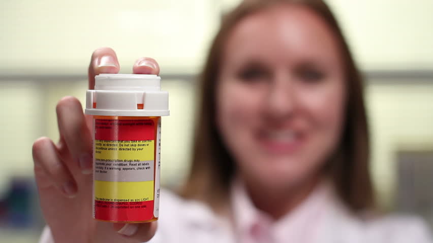 Pharmacist holding prescription bottle, shift focus