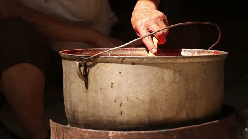 Farm tomato juice cooking. Old woman mixes the juice. 