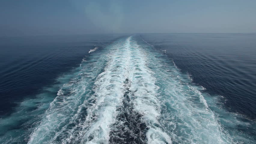 Ocean and Mediterranean Sea wake behind large Cruise ship. Hazy due to pollution smoke from smoke stacks and engine. Horizon in distance.