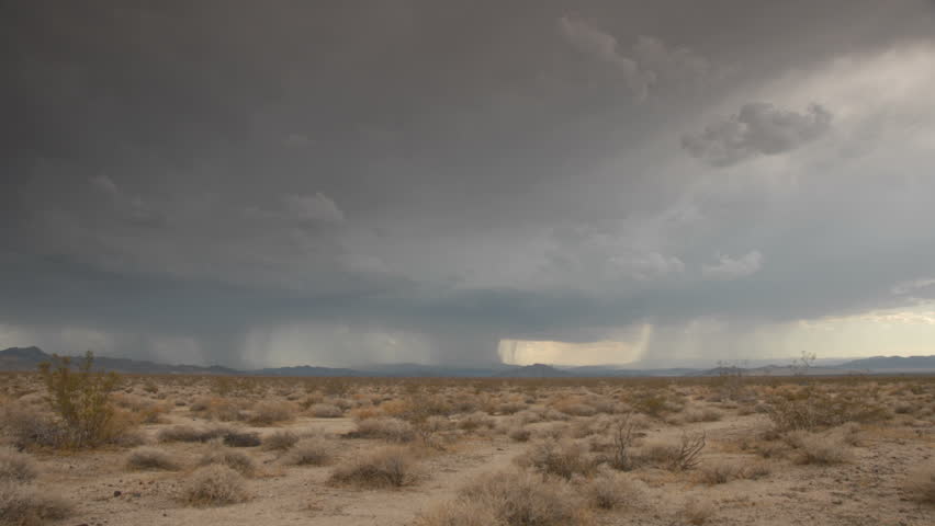 Menacing storm clouds and rain spouts cross a California desert.
