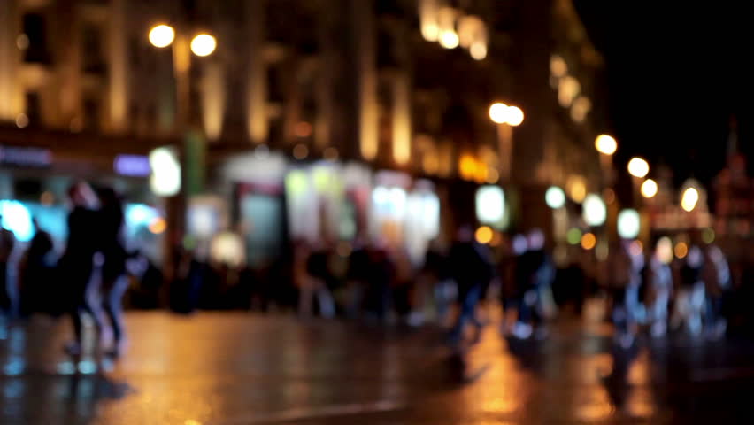 Defocused people go on a night street