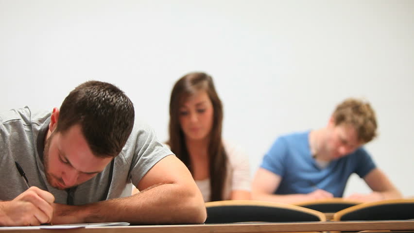 Handsome student taking notes in a classroom