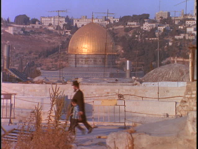 A Jewish man and his son walk past the Dome of the Rock in Jerusalem.