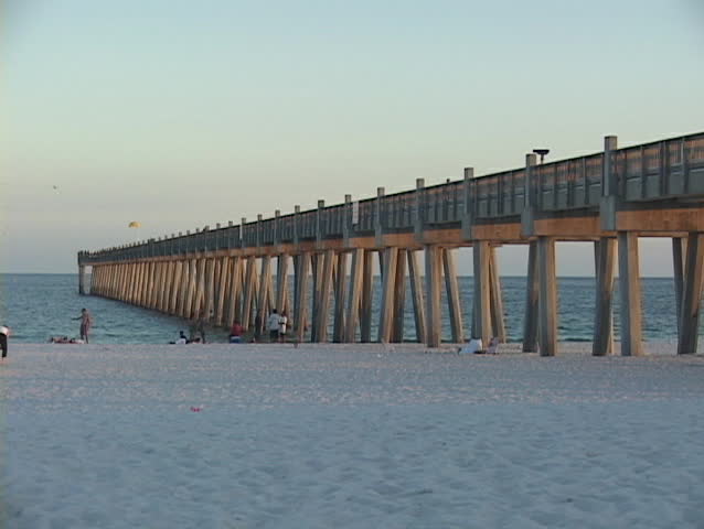 Pier pillars extend from a sandy shore to the ocean.