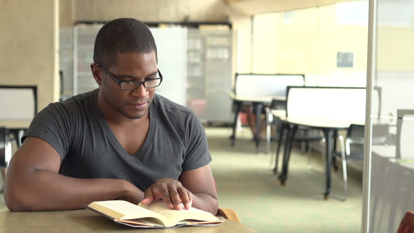 Male reading book smiles at camera