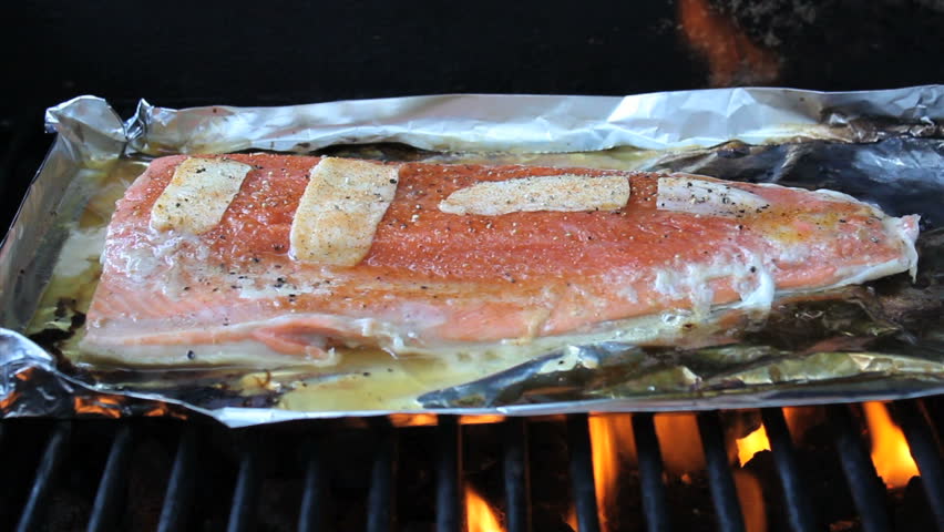 Cooking fresh caught salmon with slabs of butter and spices on the backyard barbecue for a summer treat.