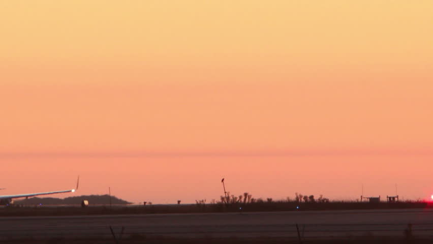 HD footage of a twin engine plane taking off in silhouette against an orange sky.