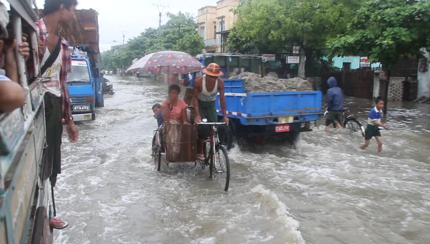 MANDALAY, MYANMAR - AUGUST  20: Vehicle and foot traffic on a flooded street circa August 20, 2011, Mandalay, Myanmar. 