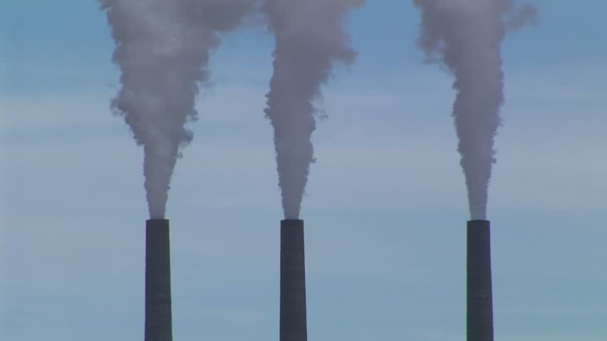 CU of three smokestacks belching fumes in an Arizona desert.