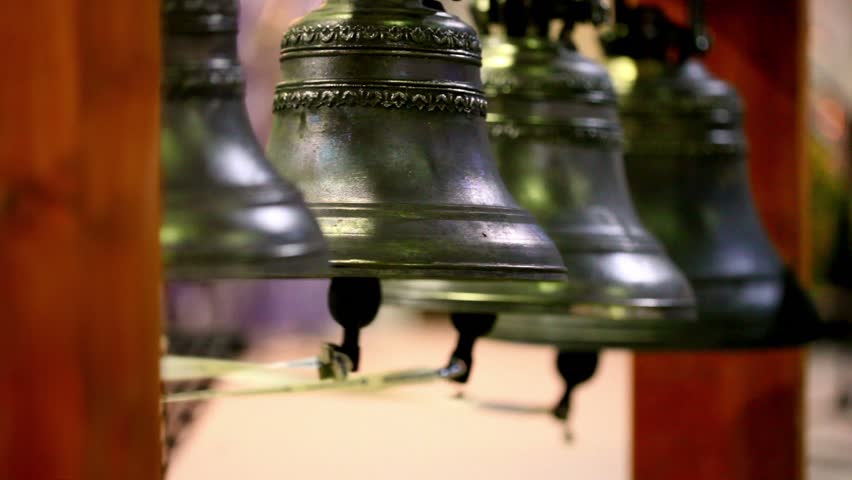 Four bells hangs on wooden frame and rings, close-up view