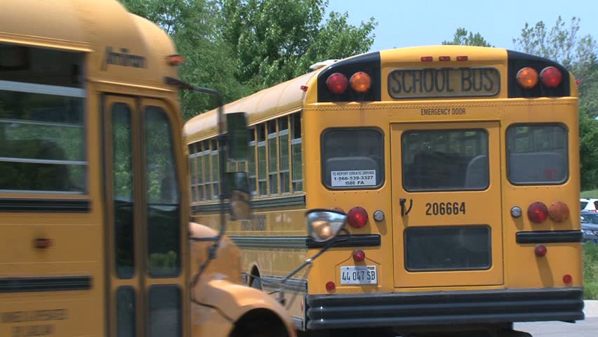 CALIFORNIA - CIRCA 2010: Two school bus leave the school parking lot, circa 2010 in California.